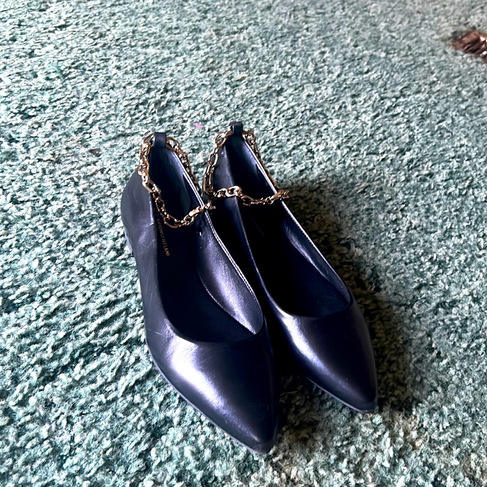 Pointed toe black flats with a golden anklet chain.